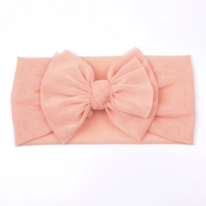 Detailed macro view of soft peach mesh bow headband for babies with breathable fabric
