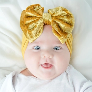 Détail d'un bébé portant un bandeau avec nœud en velours moutarde doux pour photo