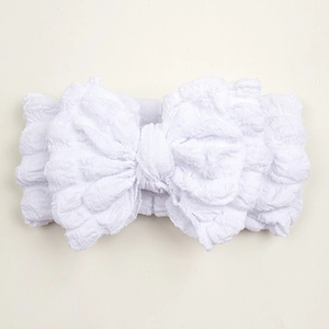 Detailed macro view of white textured cotton baby headband with a large decorative bow