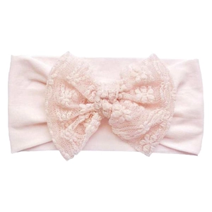 Detail view of the soft light pink baby headband with a large delicate lace bow design