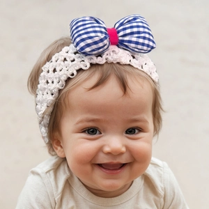 Détail du bandeau en crochet blanc pour bébé avec un grand nœud vichy bleu et blanc