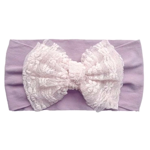 Detailed macro view of an infant headband featuring intricate cream floral lace bow detail