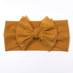 Detail of soft mustard yellow mesh baby headband featuring a large double-layer bow