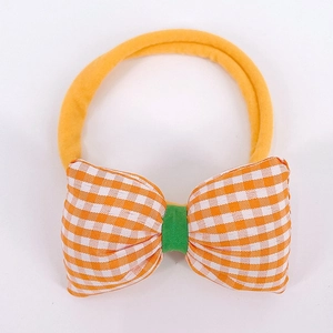 Detailed shot of yellow nylon baby headband featuring an orange checkered bow design