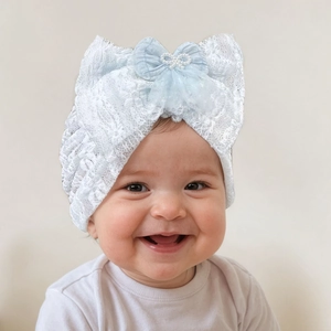 Close-up of a baby lace turban hat with large bow and pearl detail in light blue
