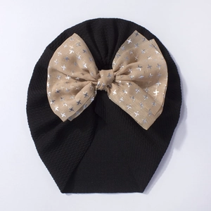 Close-up of baby beanie with champagne mesh bow and silver star prints on ribbed fabric