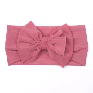 Detailed close-up of soft mesh fabric and large bow on dusty pink baby headband