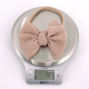 Détail du bandeau léger pour bébé avec nœud pesant 12,7g sur une balance électronique