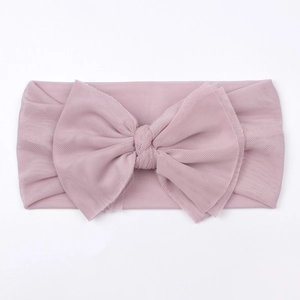 Close-up detail of soft pink mesh texture and 3D layered bow on infant headband