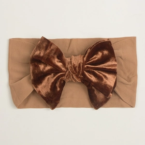 Détail d'un bandeau bébé avec un nœud en velours marron doux et un tissu en nylon élastique