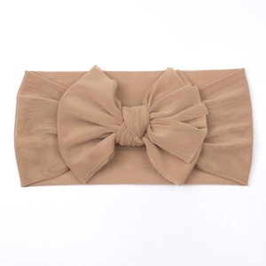 Close-up of soft mesh baby headband with a large bow in apricot color for infants