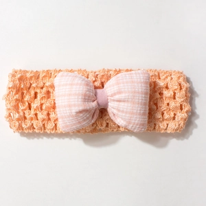 Détail macro du bandeau élastique orange ajouré avec nœud à carreaux rose et blanc