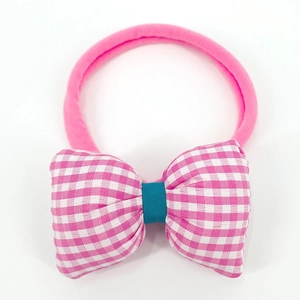 Detail of pink plaid bow baby nylon headband with teal knot on a white background