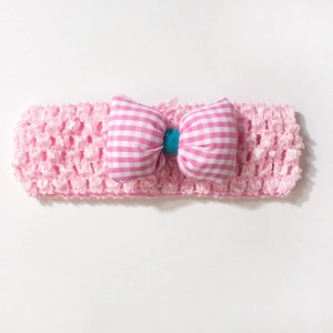 Détail d'un bandeau pour bébé en tricot rose avec un grand nœud vichy et centre bleu sarcelle