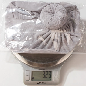 Gray pleated newborn turban hat being weighed on a scale at 32.3g for lightweight comfort