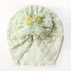 Detail of mint green baby turban hat featuring delicate lace and pearl bow ornament