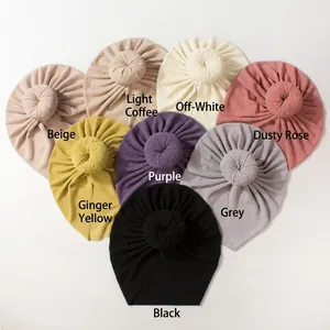 Multiple colors of ribbed knit baby turban hats with stylish donut knots in a neat row
