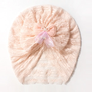 Detail of pink lace baby hat showing breathable mesh fabric and pearl bow decoration