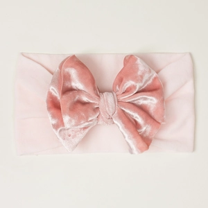 Détail du nœud en velours rose sur un bandeau élastique doux pour bébé, vue rapprochée