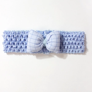 Gros plan sur le bandeau bébé au crochet bleu clair avec un nœud à carreaux bleu et blanc