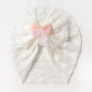 Detail of baby lace turban with pink bow, pearl accents and violet mesh embellishment