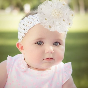 Détail du bandeau en dentelle pour bébé avec fleur en tulle et paillettes dorées