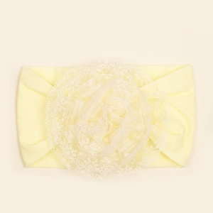 Detail van zachte lichtgele babyhoofdband met gelaagde kanten bloem en elastiek