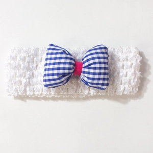 Gros plan d'un bandeau bébé élastique blanc avec nœud à carreaux bleu et rose rouge