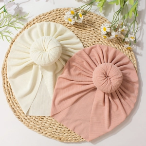Soft ribbed baby donut beanies in cream and dusty rose pink with cute top knot design