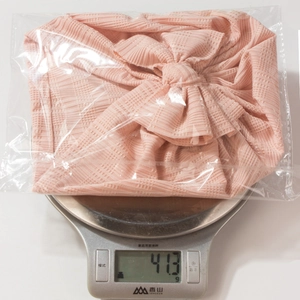 Bandeau bébé en tricot rayé rose avec grand nœud, pesé sur une balance de précision