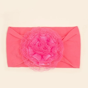 Detail van een zachte elastische roze baby hoofdband met een grote gelaagde kanten bloem