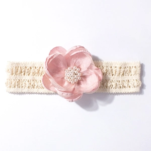 Détail d'un bandeau en dentelle pour bébé avec fleur en satin rose et perles