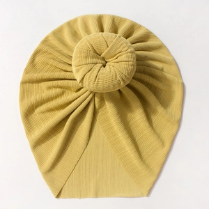 Detail of ginger yellow ribbed knit baby turban featuring a round donut knot design