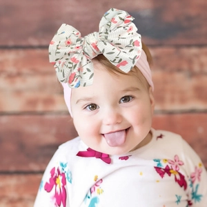 Nahaufnahme eines Babys mit rosa Nylon-Stirnband und großer floraler Schleife im Detail