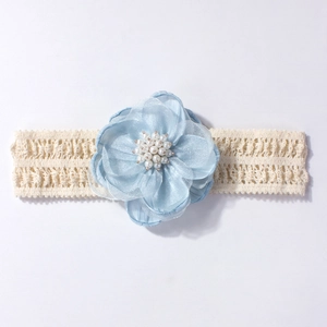 Détail d'un bandeau fleur en organza bleu clair avec perles et dentelle pour bébé