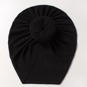 Close-up of black ribbed knit baby turban hat with a large donut knot on white background