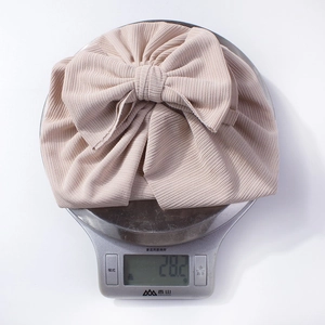 Détail d'un bonnet à nœud côtelé pour bébé pesant 28,2 grammes sur une balance