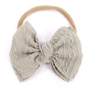Détail de la texture gaufre tricotée sur le nœud vert sauge d'un bandeau de bébé