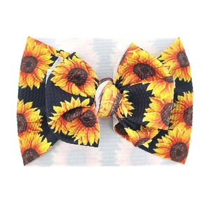 Detail eines breiten Baby-Stirnbands mit Sonnenblumenmuster und großer Schleife