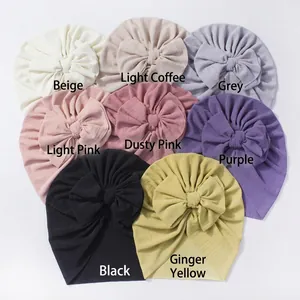 Vue à plat de bonnets côtelés pour bébé avec de grands nœuds en huit couleurs pastel