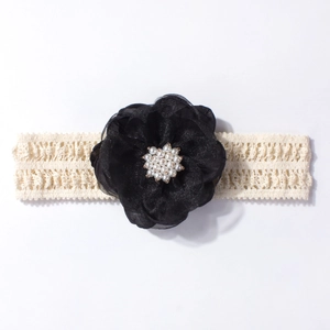 Détail du bandeau en dentelle pour bébé avec fleur en mousseline et perles blanches