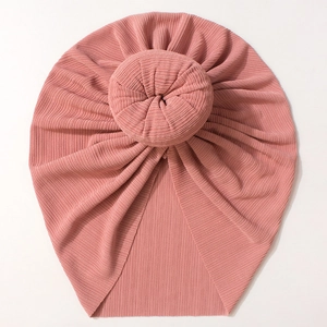 Detailed view of pink ribbed knit baby turban featuring a round donut knot design