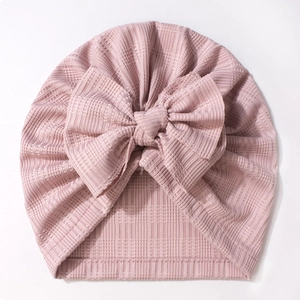 Détail du bonnet côtelé rose poudré pour bébé orné d'un grand nœud décoratif doux
