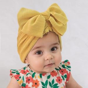 Gros plan détaillé d'un bonnet turban jaune côtelé pour bébé avec un grand double nœud