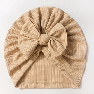 Détail du bonnet turban bébé avec texture côtelée et grand nœud en tissu beige doux