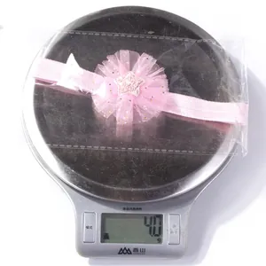 Detail of baby elastic headband with pink mesh flower and sequined star weighing 4.0 grams