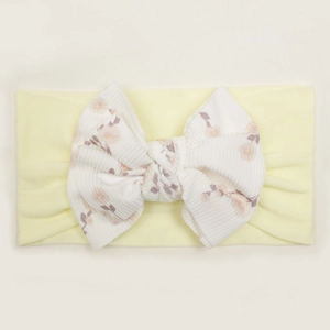 Close-up of baby nylon headband with large white ribbed bow featuring floral patterns