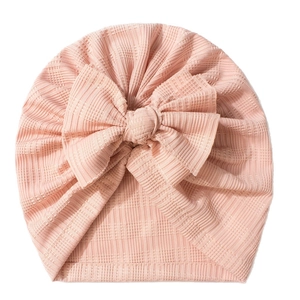 Bonnet turban rose à côtes pour nouveau-né avec un grand nœud sur fond blanc