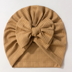 Vue détaillée du bonnet turban pour bébé en maille côtelée camel avec un grand nœud