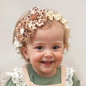 Close-up of baby lace headband featuring leopard print fabric flowers and button detail